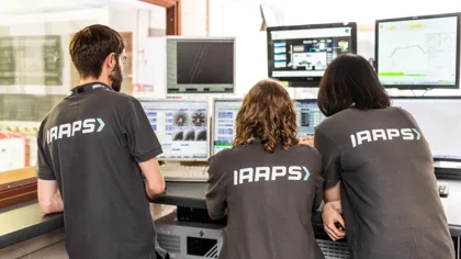 Three people working at a computer with IAAPS logo on their tops