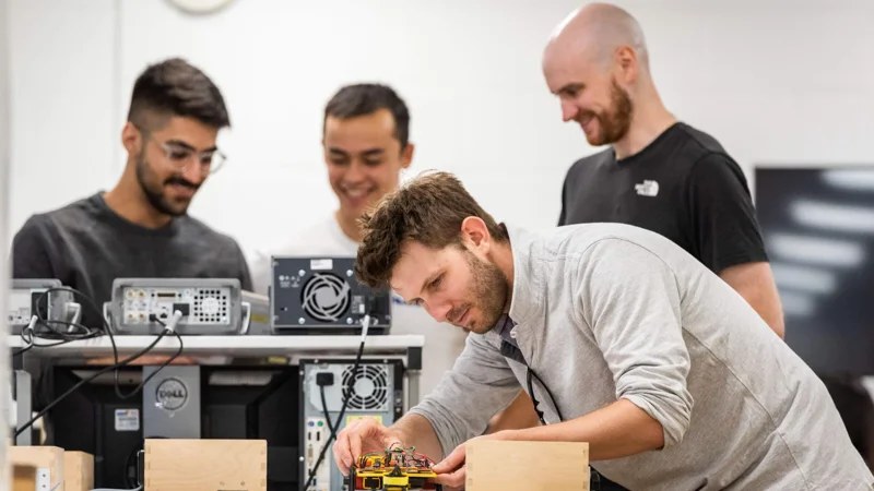 Team of men working, with one handling a circuit board